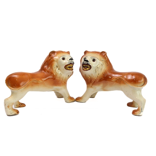 79 - A large opposing pair of late 19th century Staffordshire lions: each with glass eyes, open mouthed a... 