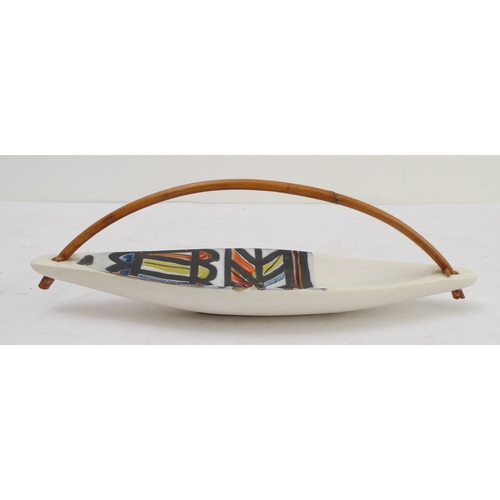 20 - A circa 1950s kayak-shaped Vallauris dish: bowed bamboo handle above a brightly decorated abstract d... 