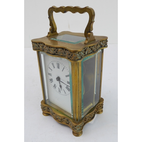 291 - A late 19th to early 20th century French gilt-brass and glass-sided carriage clock: the shaped handl... 