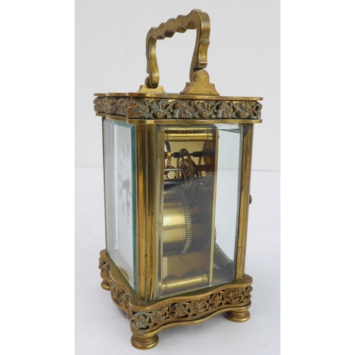 291 - A late 19th to early 20th century French gilt-brass and glass-sided carriage clock: the shaped handl... 