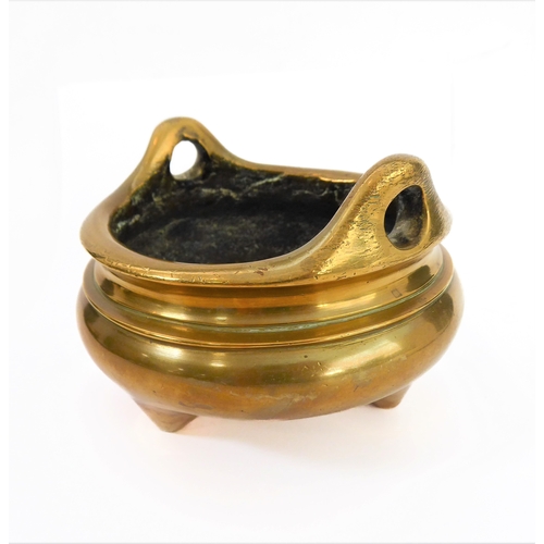 111 - A Chinese polished brass/bronze two-handled tripod censer in 17th century style: reign marks within ... 