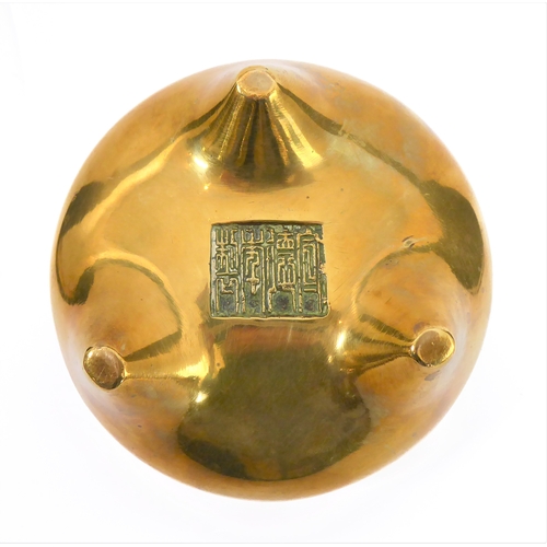 111 - A Chinese polished brass/bronze two-handled tripod censer in 17th century style: reign marks within ... 
