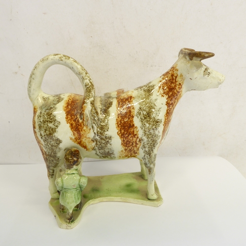 51 - A pair of early 19th century English pearlware milkmaid cow creamers: stripped brown and umber spong... 