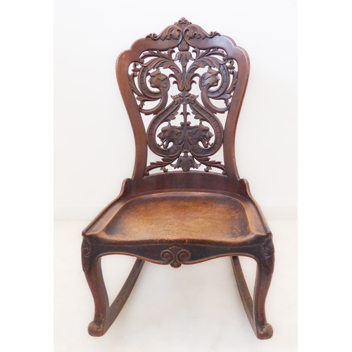 412 - An unusual 19th century continental mahogany rocking chair: the pierced back with scrolling acanthus... 