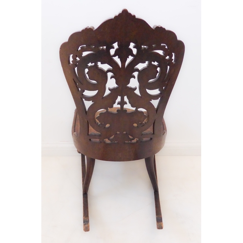412 - An unusual 19th century continental mahogany rocking chair: the pierced back with scrolling acanthus... 