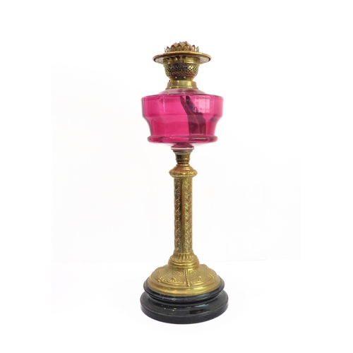 86 - A 19th century brass-mounted oil lamp with cranberry glass reservoir and crimped shade: foliate deco... 