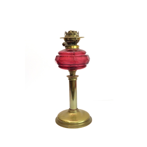 88 - A 19th century brass and cranberry glass oil lamp: the large crimped shade above a faceted cranberry... 