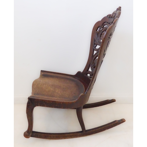 412 - An unusual 19th century continental mahogany rocking chair: the pierced back with scrolling acanthus... 