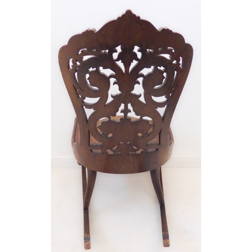 412 - An unusual 19th century continental mahogany rocking chair: the pierced back with scrolling acanthus... 