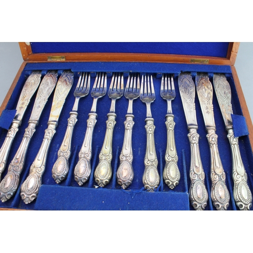 76 - An early 20th century walnut-cased set of 12 silver-plated fish eaters; the blades and fork heads en... 