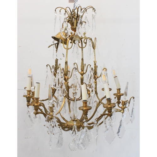 56A - A large and showy pair of gilt metal and cut-glass, 12 light chandeliers: varying tiers with individ... 