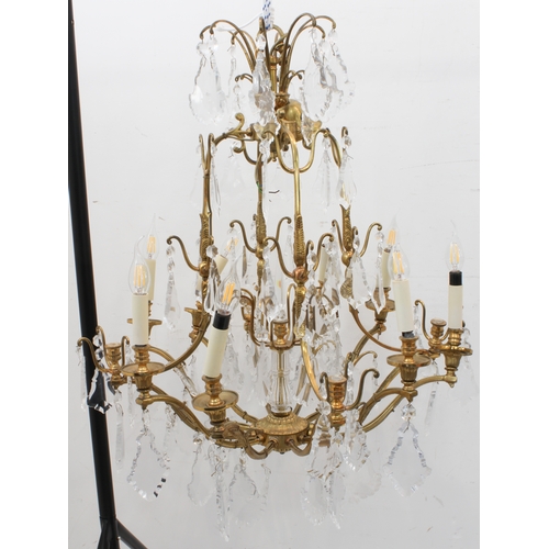 56A - A large and showy pair of gilt metal and cut-glass, 12 light chandeliers: varying tiers with individ... 