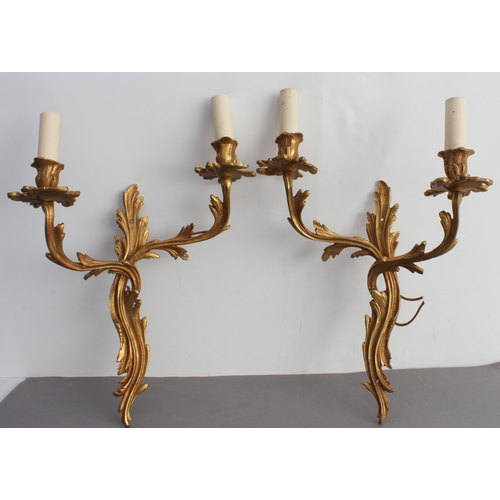 52 - A pair of early 20th century gilt-metal two-light wall appliques in Louis XV style and carved as aca... 