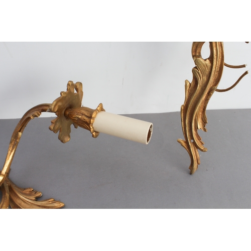 52 - A pair of early 20th century gilt-metal two-light wall appliques in Louis XV style and carved as aca... 