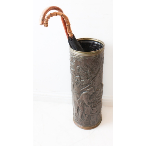 50 - A large and decorative embossed-brass cylindrical umbrella-stand with two umbrellas (23 cm in diamet... 