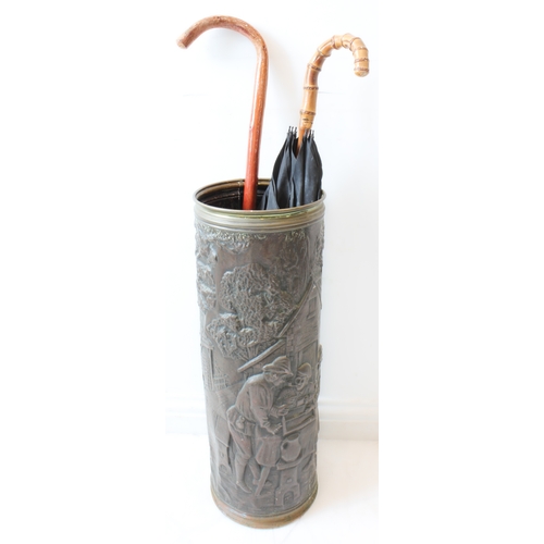 50 - A large and decorative embossed-brass cylindrical umbrella-stand with two umbrellas (23 cm in diamet... 