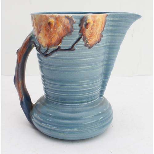 12 - Four ceramic jugs:
 an Art Deco Shelley example with reeded body and varying colours (34 cm high);
 ... 