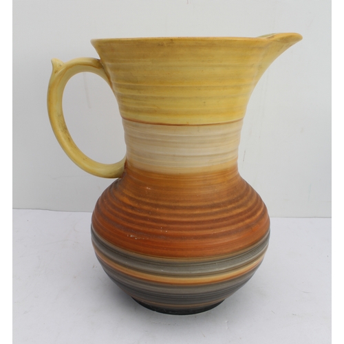 12 - Four ceramic jugs:
 an Art Deco Shelley example with reeded body and varying colours (34 cm high);
 ... 