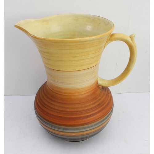 12 - Four ceramic jugs:
 an Art Deco Shelley example with reeded body and varying colours (34 cm high);
 ... 