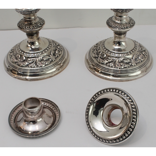 181 - A pair of modern, hallmarked silver, weighted candlesticks: spreading circular feet decorated with s... 