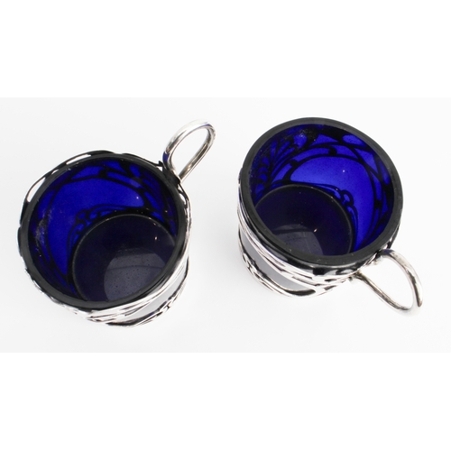 187 - A set of four coffee cans with cobalt-blue glass liners and pierced hallmarked silver outers in Art ... 