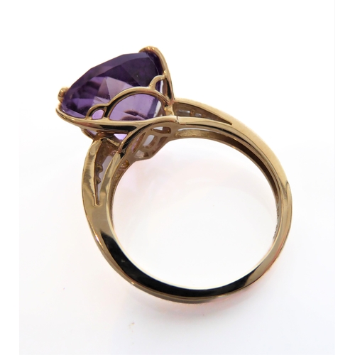 211 - A 9-carat yellow gold dress ring: centrally set with a trillion-cut amethyst of good colour, unusual... 