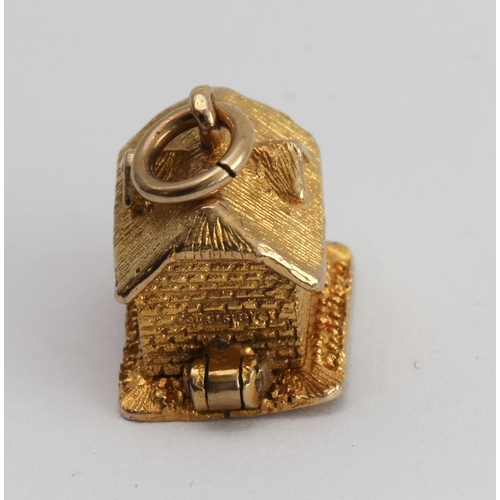 218 - A 9-carat yellow gold charm modelled as a cottage opening on a hinge to reveal a bear asleep in bed ... 