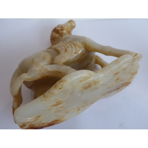 38 - Qing Dynasty (1644-1911) - a large and heavy pale-celadon and russet jade carving of a saddled horse... 