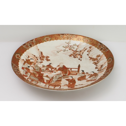 67 - A large Japanese earthenware Kutani dish
 Meiji period (1868-1912), finely painted with a feasting s... 