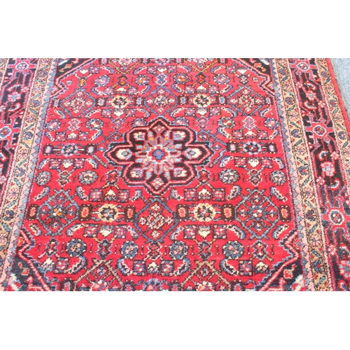 591 - A Persian Hamadan rug; red ground with blue central medallion, floral sprays surrounded by four bord... 