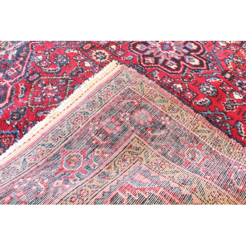 591 - A Persian Hamadan rug; red ground with blue central medallion, floral sprays surrounded by four bord... 