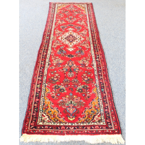 593 - A Persian Hamadan runner; red ground with ivory central medallion surrounded by flowers (294 x 89 cm... 