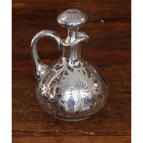 192 - A late 19th/early 20th century silver overlay jug and stopper: the flowerhead-decorated stopper abov... 