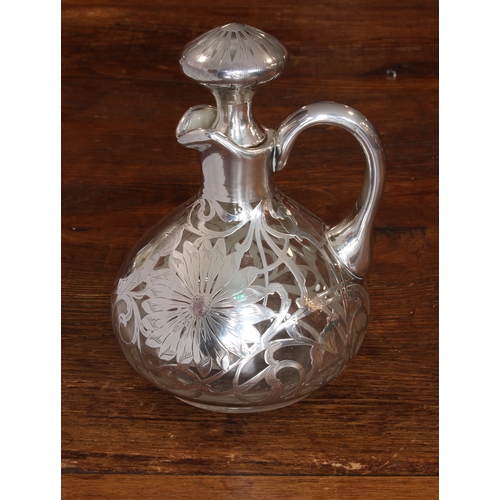 192 - A late 19th/early 20th century silver overlay jug and stopper: the flowerhead-decorated stopper abov... 