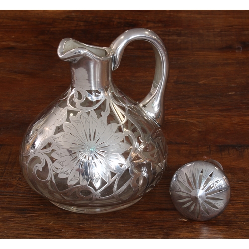 192 - A late 19th/early 20th century silver overlay jug and stopper: the flowerhead-decorated stopper abov... 