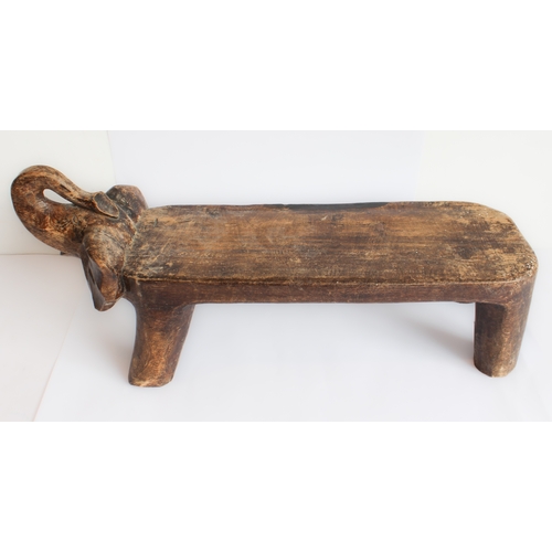 125 - An African stool or seat carved from a single piece of softwood modelled as an elongated trumpeting ... 