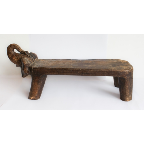 125 - An African stool or seat carved from a single piece of softwood modelled as an elongated trumpeting ... 