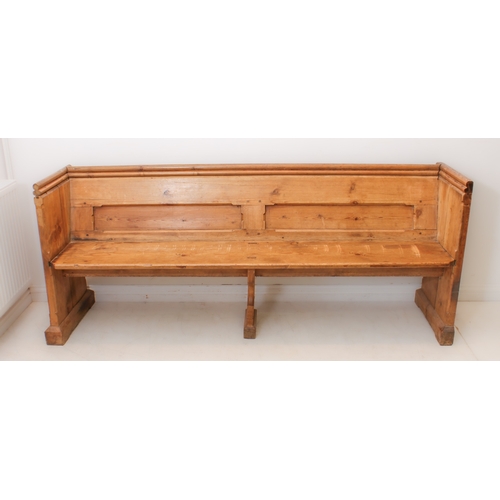 410 - A Victorian pine pew - the chamfer-panelled back with a trefoil shaped handrail above, over a plain ... 