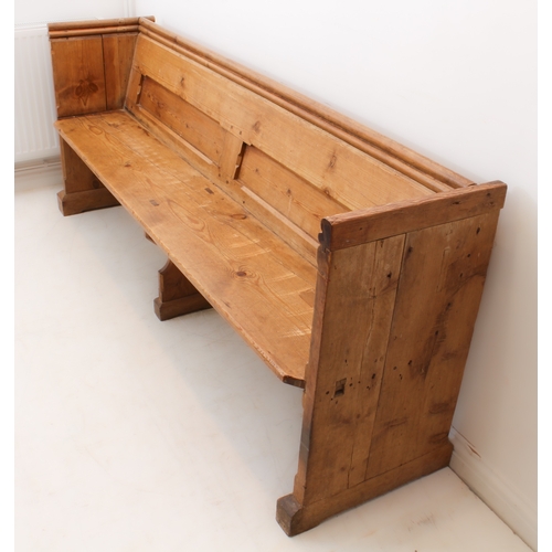 410 - A Victorian pine pew - the chamfer-panelled back with a trefoil shaped handrail above, over a plain ... 