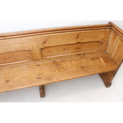 410 - A Victorian pine pew - the chamfer-panelled back with a trefoil shaped handrail above, over a plain ... 