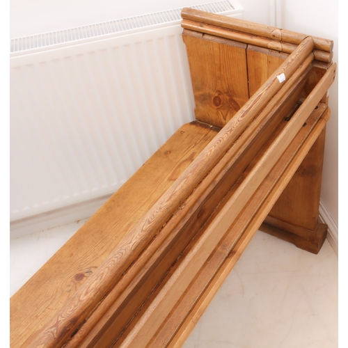 410 - A Victorian pine pew - the chamfer-panelled back with a trefoil shaped handrail above, over a plain ... 