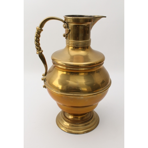 583 - A large Edwardian brass ewer in Arts & Crafts style - the girdled, bun-shaped body on a pedestal foo... 