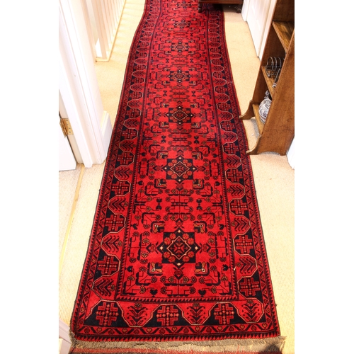 563 - An extremely long Afghan Kundoz runner - retailed by G. H. Frith Ltd., with a row of 21 dark blue sq... 