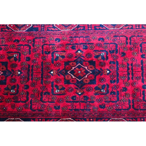 564 - An Afghan Kundoz rug - with three square medallions and all over floral decoration on a red field, w... 