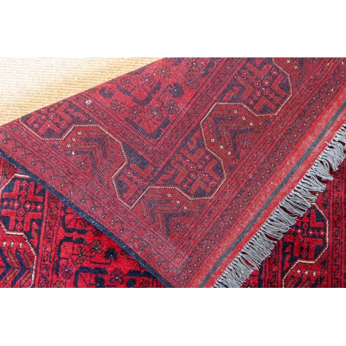 564 - An Afghan Kundoz rug - with three square medallions and all over floral decoration on a red field, w... 