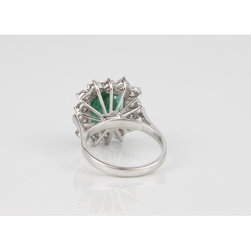 184 - An 18ct white gold, emerald and diamond cluster ring - stamped '18K', the 11 x 9mm. rectangular cush... 