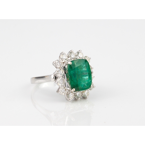 184 - An 18ct white gold, emerald and diamond cluster ring - stamped '18K', the 11 x 9mm. rectangular cush... 