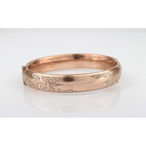 225 - A silver and rolled gold hollow, hinged bangle, c.1900 - chased with foliate scrolls.