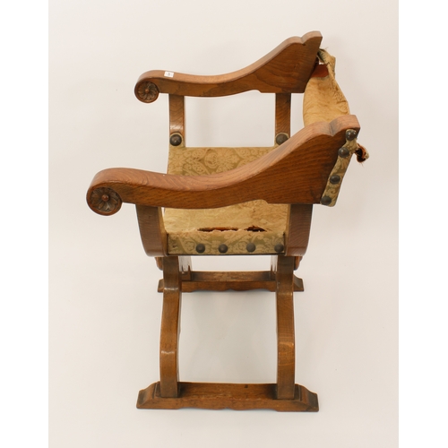 416 - A late 19th century mid-oak and leather x-framed chair - the leather back and slung seat covered in ... 