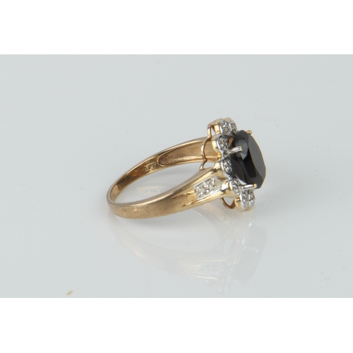 174 - A 9ct yellow gold, sapphire and white stone cluster ring - the oval cut sapphire, approx. 9.5 x 7.75... 